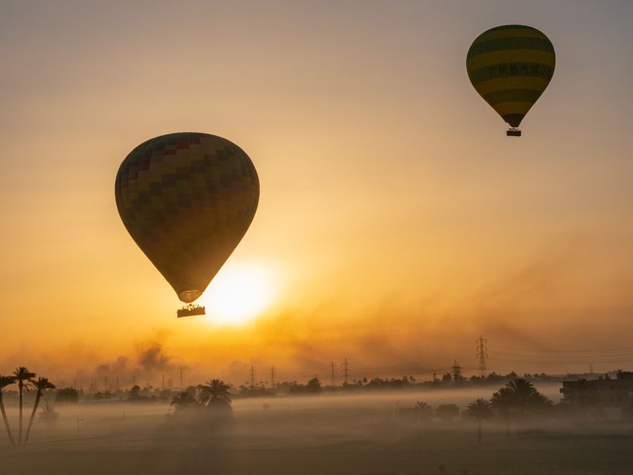 Hot air balloons drifting over mist-covered countryside at sunrise