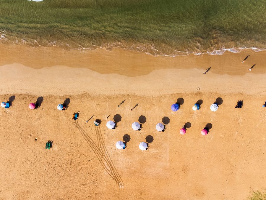 Rows of beach umbrellas on the wide sand at Bentota seen from above