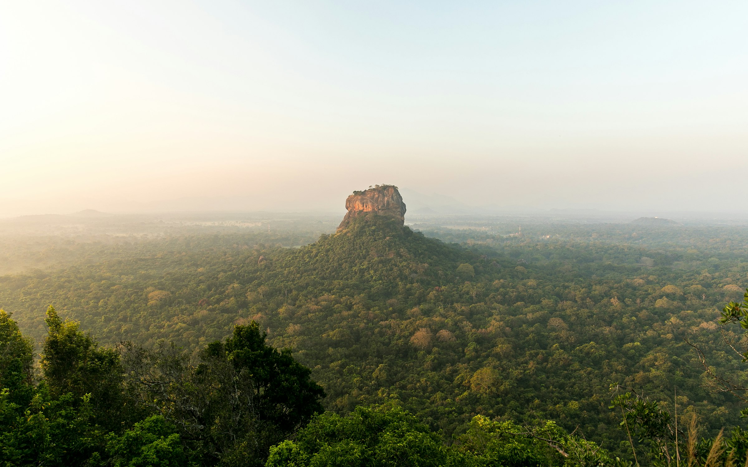 Sigiriya Rock rising above mist and jungle at dawn in Sri Lanka's Cultural Triangle