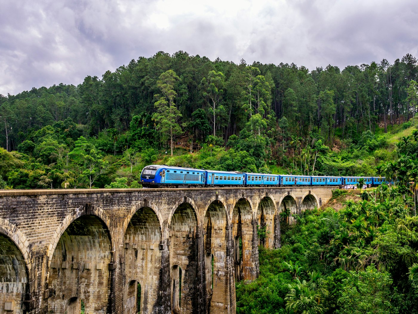 A blue train crossing the Nine Arch Bridge through tea country near Ella, Sri Lanka