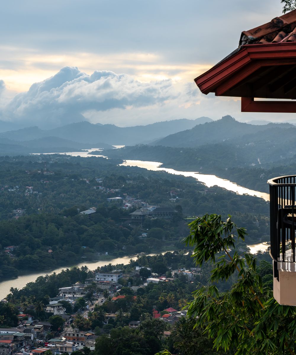 The terrace of a boutique hotel looking out over a wide river valley at dusk.